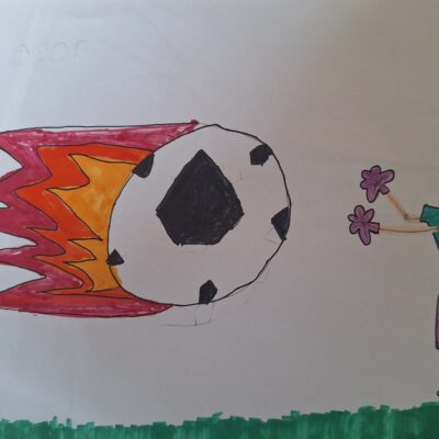 Eine Kinderzeichnung eines Fußballspiels zeigt ein Mädchen in einem rosa Trikot, das einen brennenden Fußball in Richtung eines lächelnden Torwarts in einem grünen Trikot schießt, der neben einem Tor steht. Der Fußballplatz hat grünes Gras.