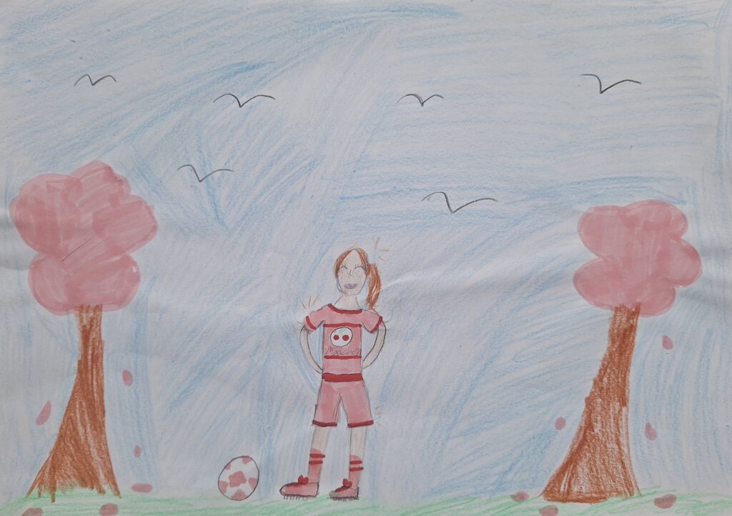 Kinderzeichnung eines lächelnden Mädchens mit orangefarbenen Haaren, das im Gras zwischen zwei rosafarbenen Bäumen steht, ein rot-weißes Outfit trägt und einen Fußball in der Nähe hat. Der Himmel ist blau mit ein paar fliegenden Vögeln.